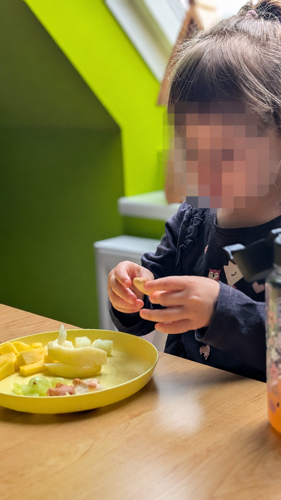 Kind hält ein Obststück am Tisch