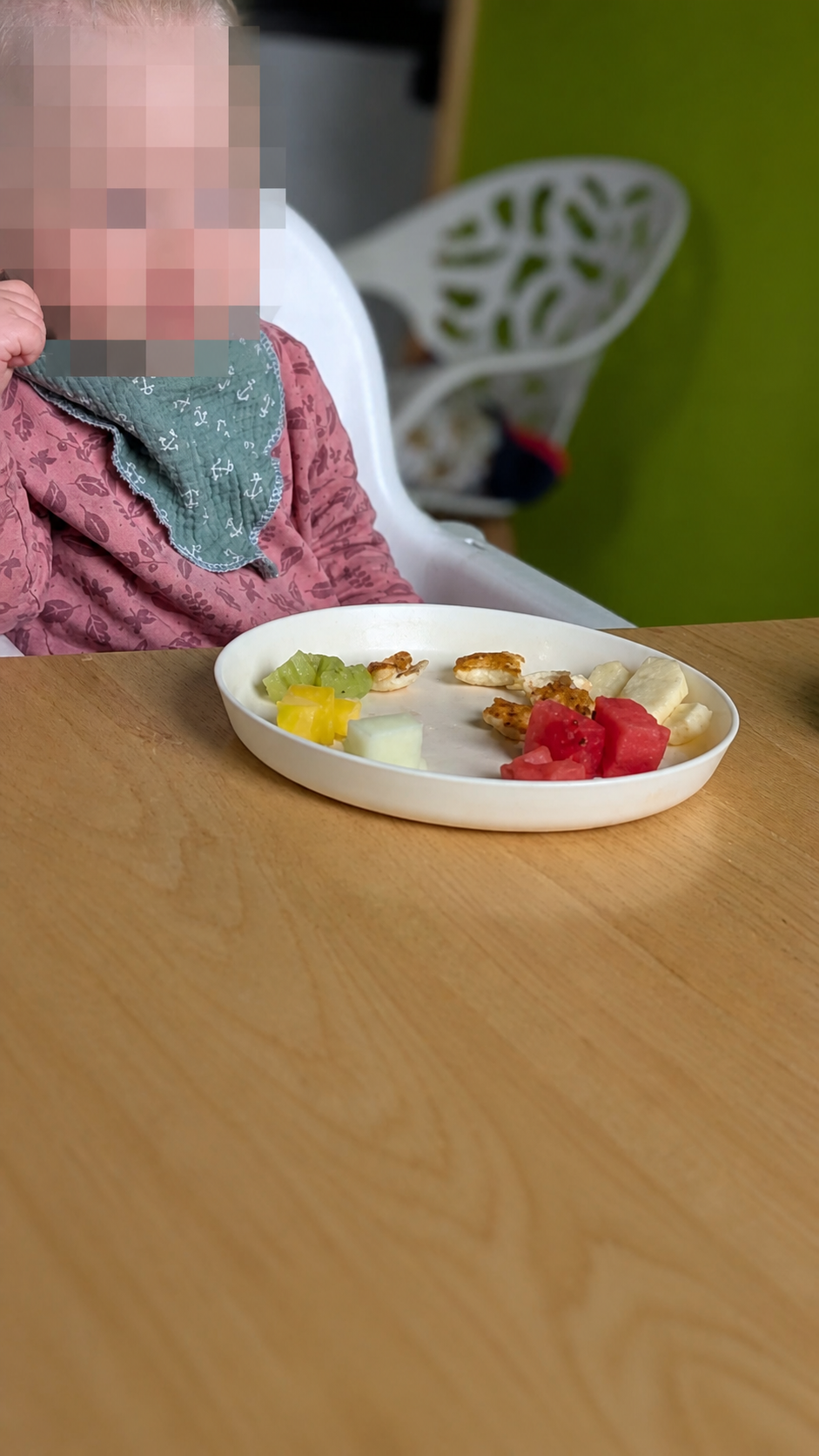 Kind isst am Tisch ein Stück Wassermelone